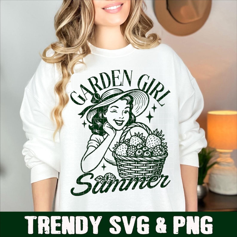 Puede incluir: Sudadera blanca con un dise&ntilde;o verde de una mujer con sombrero de sol, gui&ntilde;ando un ojo y sosteniendo una cesta de bayas. El texto dice "GARDEN GIRL Summer". Debajo del dise&ntilde;o est&aacute; el texto "TRENDY SVG & PNG".