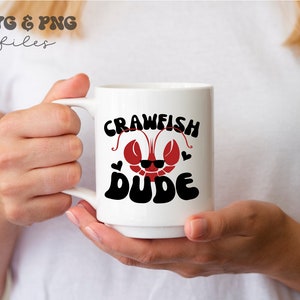 May include: White ceramic mug with a red crawfish wearing sunglasses and the text "Crawfish Dude" in black.