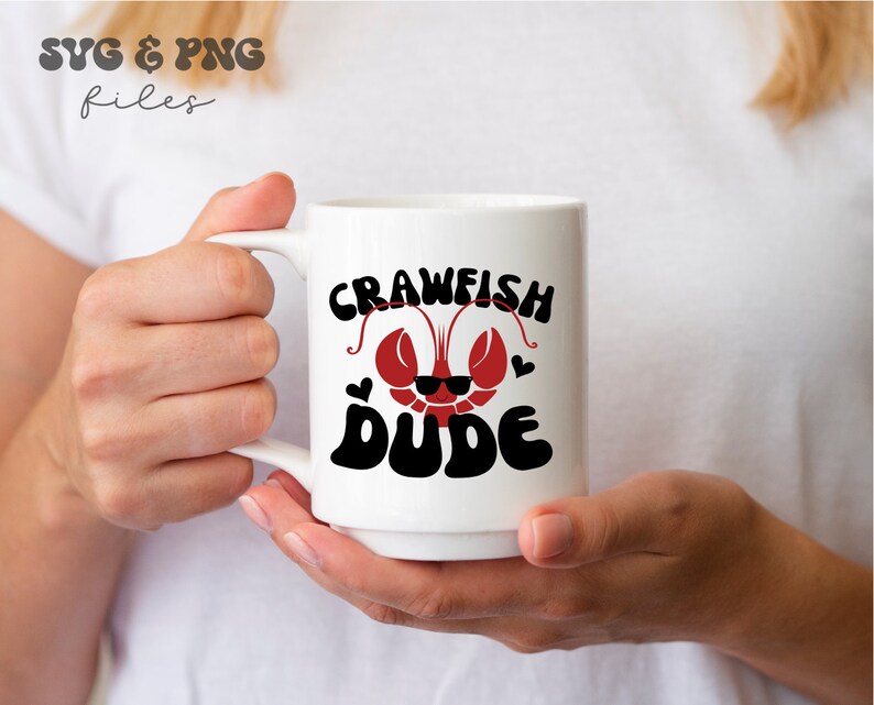 May include: White ceramic mug with a red crawfish wearing sunglasses and the text "Crawfish Dude" in black.