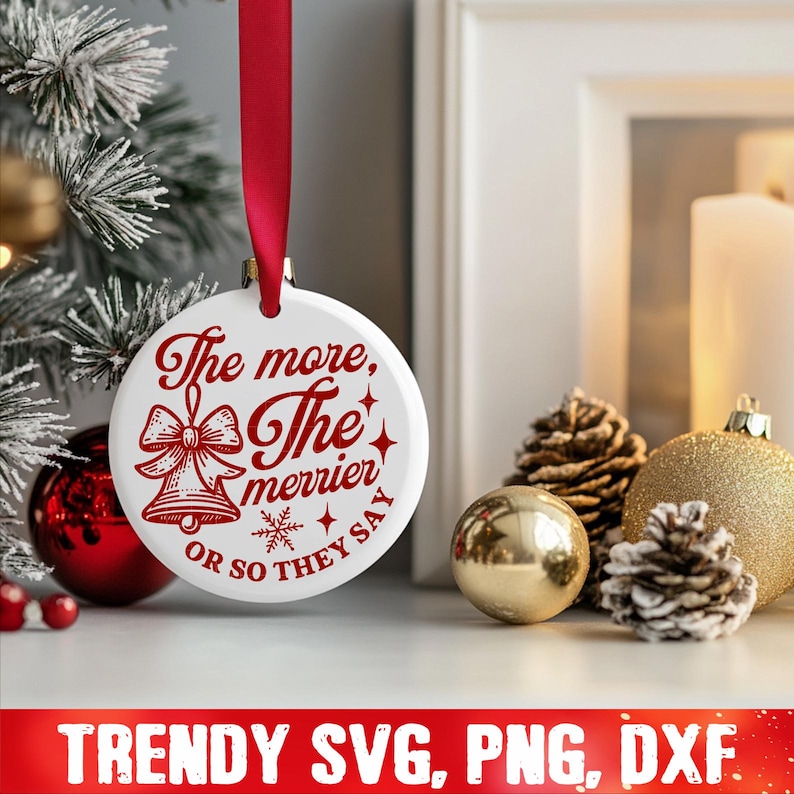 May include: White Christmas ornament with red text that reads "The more, the merrier or so they say". The ornament features a red bow and two bells.