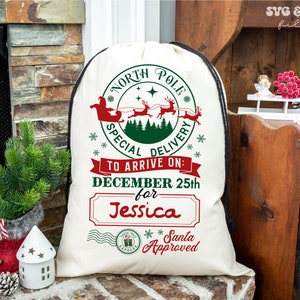 May include: A cream-coloured drawstring sack featuring a red and green graphic of Santa Claus in a sleigh with reindeer. The text reads North Pole Special Delivery, To Arrive On: December 25th for Jessica, and Santa Approved with a postmark stamp.