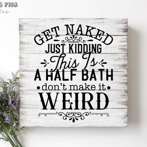 May include: A square wooden sign with a white distressed finish featuring black text that reads: GET NAKED JUST KIDDING This Is A HALF BATH don't make it WEIRD. The sign is decorated with black flourishes and is accompanied by a small bouquet of lavender.