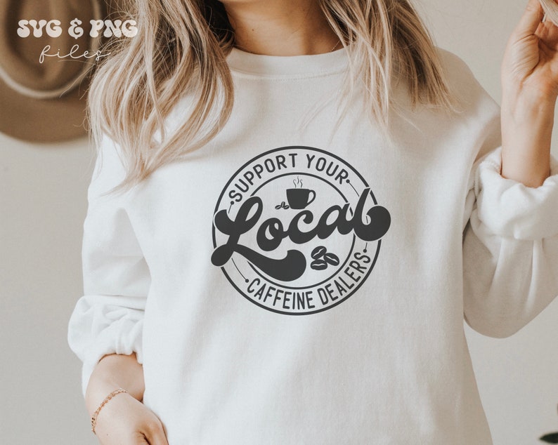 May include: White sweatshirt with a black circle graphic that says "Support Your Local Caffeine Dealers" with a coffee cup and coffee beans inside the circle.