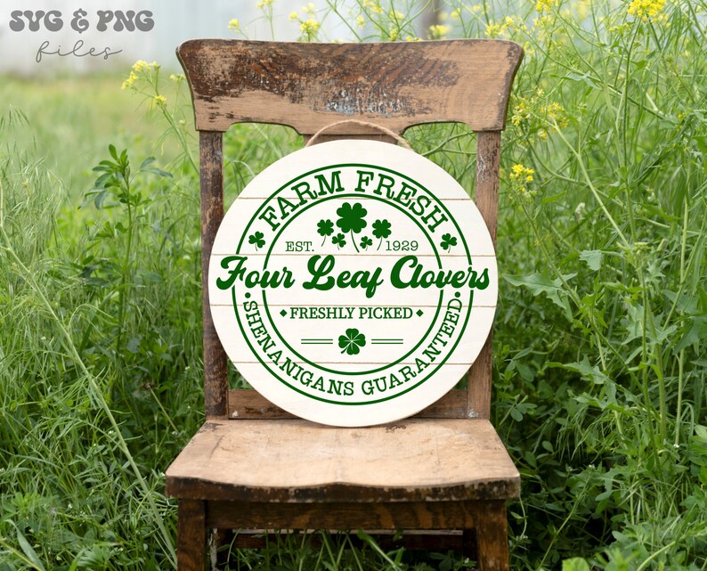 May include: A white round wooden sign with green text that reads "FARM FRESH EST. 1929 Four Leaf Clovers FRESHLY PICKED SHENANIGANS GUARANTEED". The sign has a rustic woodgrain pattern and is decorated with green four-leaf clover designs.