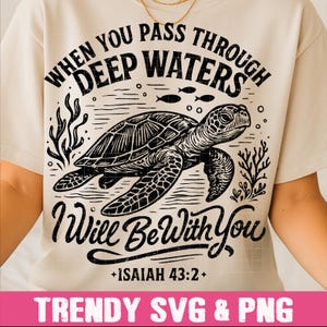 May include: Cream-colored t-shirt featuring a black graphic of a sea turtle swimming in water, with the text "WHEN YOU PASS THROUGH DEEP WATERS I Will Be With You +ISAIAH 43:2+". The bottom of the shirt has the text "TRENDY SVG & PNG".