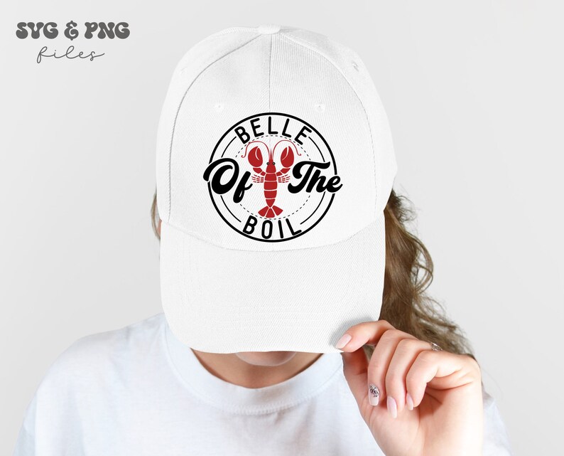 May include: White baseball cap with a black and red design that says "Belle of the Boil" with a lobster illustration.