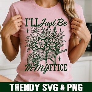 Puede incluir: Camiseta rosa claro con un dise&ntilde;o verde de una carretilla llena de flores y el texto "I'll Just Be In My Office". En la parte inferior, se lee "TRENDY SVG & PNG".