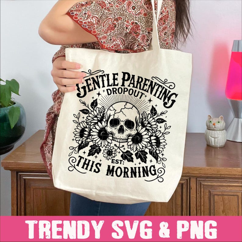 May include: A white tote bag with a black graphic design. The design features a skull with flowers and the text "Gentle Parenting Dropout Est: This Morning".