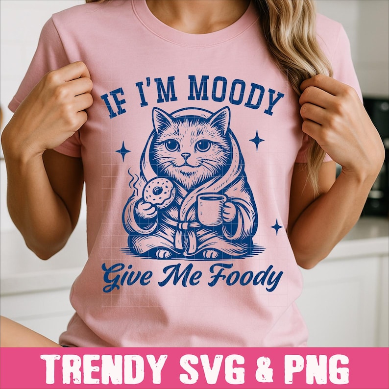 May include: Pink t-shirt with a blue illustration of a cat in a robe holding a donut and a cup of coffee. The text "If I'm Moody Give Me Foody" is printed on the shirt.