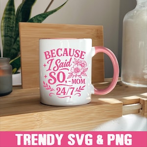 May include: White ceramic mug with a pink design that says "Because I Said So - Mom 24/7". The mug has a pink handle and is sitting on a wooden surface.