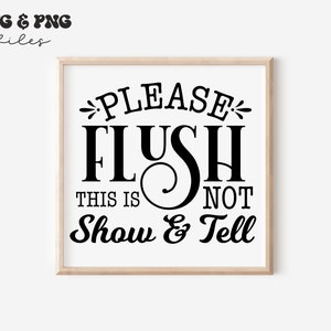 May include: A square wooden frame containing a white sign with black text that reads: PLEASE FLUSH THIS IS NOT Show & Tell. The text is arranged in multiple lines with decorative flourishes around the word PLEASE and the ampersand symbol.
