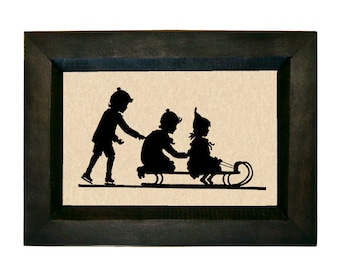 May include: A framed black and white silhouette image of three children on a sled. The child in the front is sitting on the sled, while the child in the middle is pushing the sled and the child in the back is holding on. The image is set against a beige background.