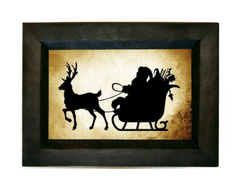 May include: A black silhouette of Santa Claus riding in a sleigh pulled by a reindeer against a beige background with a distressed texture. The image is framed in a black wood frame.