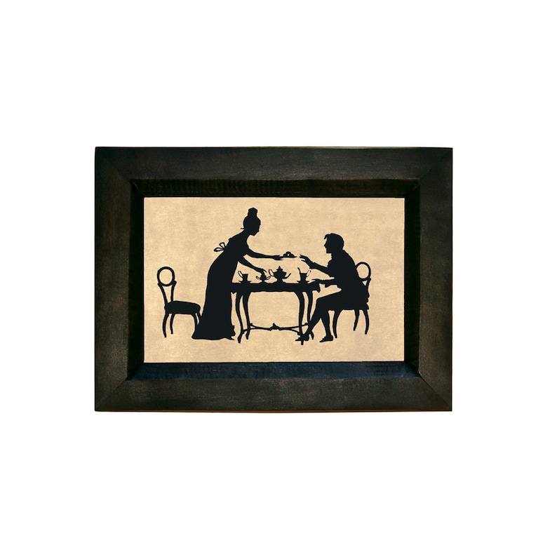Puede incluir: Una silueta negra de una pareja sentada a una mesa con una tetera y tazas. La imagen est&aacute; enmarcada en un marco negro.