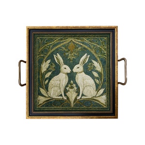 May include: A square serving tray with gold trim and two brass handles. The tray features a framed image of two white rabbits facing each other in a green and gold floral design.
