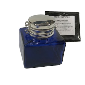 Puede incluir: Un tintero de vidrio azul con una tapa de plata y una pequeña etiqueta que dice "Black Ink Powder" con instrucciones de mezcla. La etiqueta dice que se deben usar 3 onzas de agua tibia y 1 cucharadita de polvo de tinta para obtener un color rico y agradable.