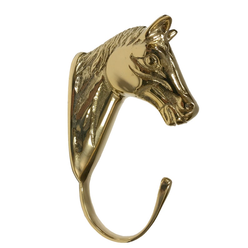 May include: A gold-toned horse head wall hook. The hook is shaped like a horse's head with a curved hook extending from the bottom.