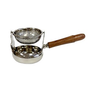 May include: Silver tea infuser with a wooden handle. The infuser has a round, perforated bowl and a smaller, round, perforated strainer inside.