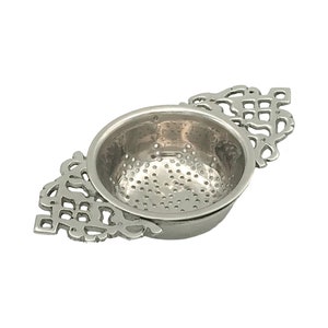 May include: Silver tea infuser with a decorative handle and a fine mesh strainer.