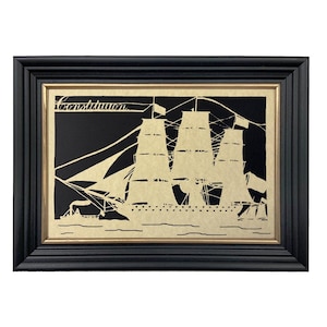 May include: Framed silhouette art of a tall ship, featuring three masts and billowing sails. The artwork is set against a black background with the word "Constitution" at the top. The frame is black with a gold inner border.