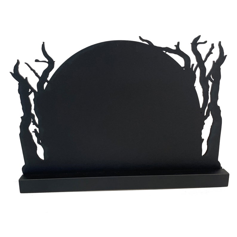 May include: Black silhouette of a moon with branches and leaves around it. The moon is on a black stand.