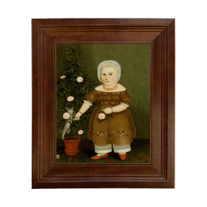 May include: A framed folk art painting of a young child in a brown dress holding a rose and interacting with a cat near a rose bush. The painting has a dark brown wooden frame and a green background.