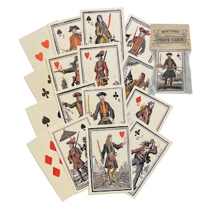 May include: A deck of historic pirate playing cards featuring vintage-style illustrations of figures in 18th-century attire, swords, and nautical symbols. The cards are displayed fanned out alongside a clear plastic pack labelled Historic Pirate Cards.