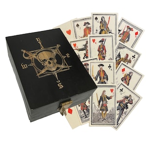 Caixa de madeira com rosas dos ventos e caveiras e cartas de baralho com tema de piratas