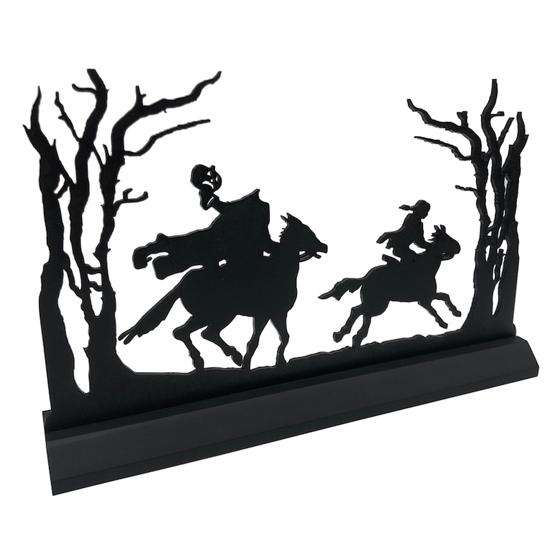May include: Black silhouette of two figures on horseback riding through a forest. The figures are in the foreground and the trees are in the background. The silhouette is mounted on a black base.