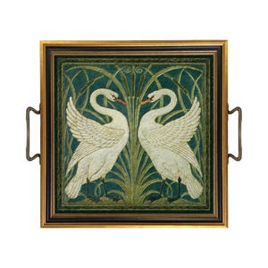 May include: A square serving tray with a gold and black frame and two metal handles. The center features a detailed illustration of two white swans facing each other, surrounded by green reeds and cattails against a dark green background.