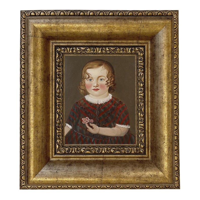 May include: A framed portrait of a young child. The child is wearing a red and black plaid dress and holding a small flower. The frame is gold with ornate detailing.