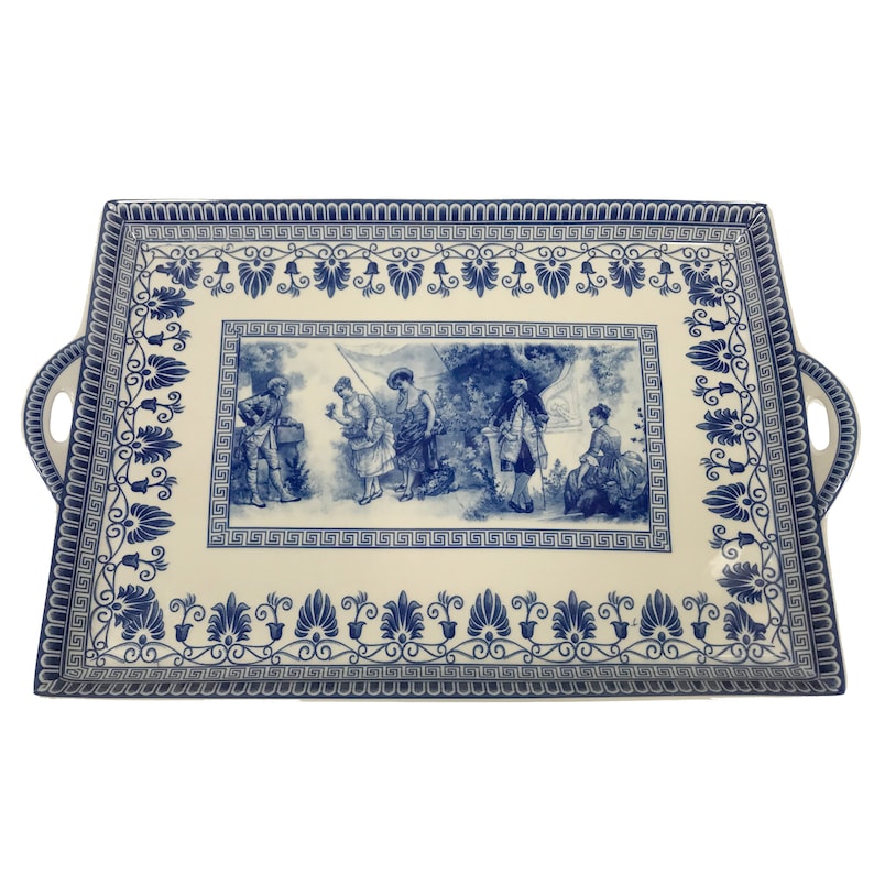 May include: A white rectangular serving tray with blue and white floral designs and a central scene of people in a garden. The tray has two handles on the sides.
