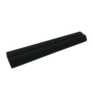 May include: Black rubber phone stand with a raised center ridge. The stand is designed to hold a phone upright.