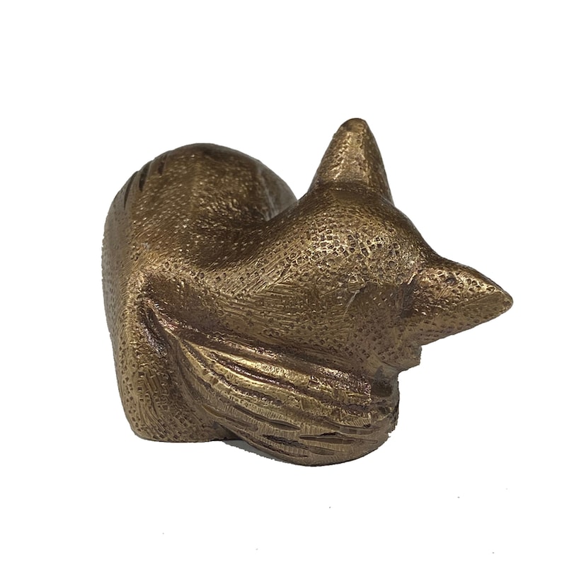 May include: A bronze sculpture of a sleeping fox. The fox is curled up with its tail wrapped around its body. The sculpture is detailed with a textured surface.