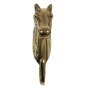 May include: A gold-toned metal horse head hook. The hook is designed to look like a horse's head with a curved hook extending from the bottom of the neck.