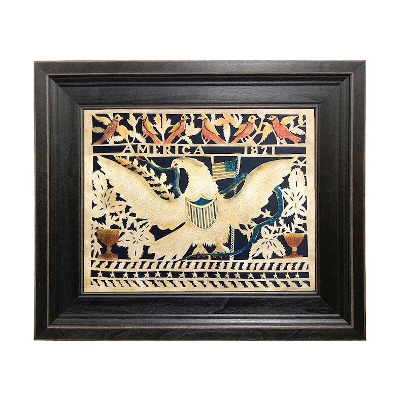Op de afbeelding: Een ingelijst papierknipsel met een centrale witte adelaar met gespreide vleugels, een schild en een kleine vlag. De tekst AMERICA 1821 staat gecentreerd boven de adelaar. Het ontwerp bevat vogels, bladeren en sterren op een donkere achtergrond.