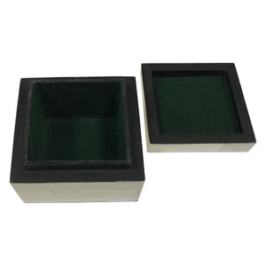 May include: Open square wooden box with a lid. The box is black and white with a green interior. The lid is off to the side. The box is empty.