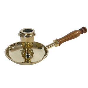 Könnte beinhalten: Ein Kerzenhalter aus Messing mit einem Holzgriff. Der Halter hat einen runden Sockel und eine Tasse für eine Kerze. Der Griff ist mit einer Metallstange am Sockel befestigt.