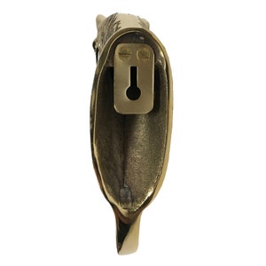 May include: A gold-toned metal hook with a decorative animal head design. The hook has a keyhole on the back for mounting.