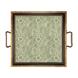 May include: Square serving tray with a black and gold frame and brass handles. The tray's interior features a green and cream floral pattern. The tray is designed for serving food and drinks.