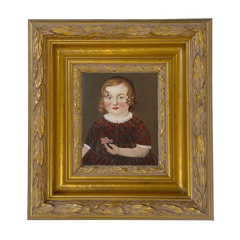 May include: A framed portrait of a young child. The child is wearing a red and black plaid dress and holding a small flower. The portrait is in a gold ornate frame.