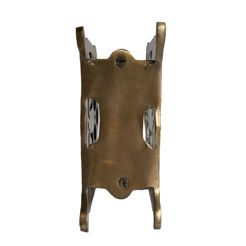 May include: A vintage brass-toned metal object with a rectangular body and curved legs. The object has two rectangular cutouts and is secured with screws. The overall design suggests a small decorative holder or stand.