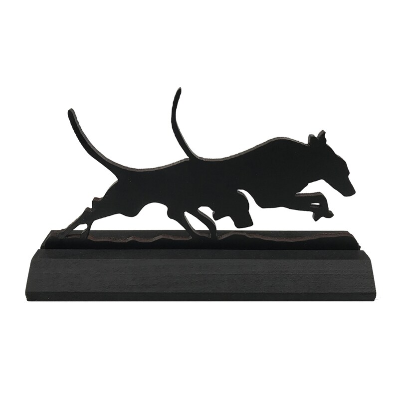 May include: Black silhouette of a dog running, mounted on a black wooden base.