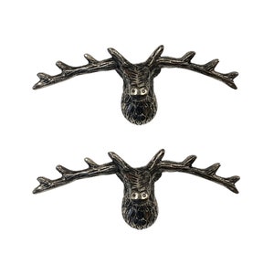 May include: Two silver metal deer head hooks with antlers. The deer heads are facing forward with their mouths closed. The antlers are spread out to the sides.