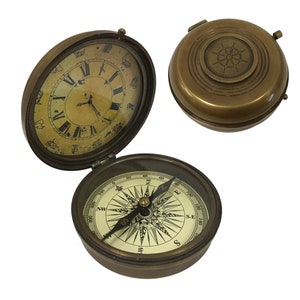 May include: A brass compass with a clock face and a compass rose. The compass is closed and the clock face is visible. The compass is open and the compass rose is visible.