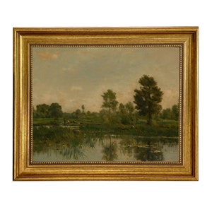 May include: A framed oil painting depicting a tranquil landscape with a lake, trees, and a cloudy sky. The lake is in the foreground, with green trees lining the banks. The sky is a pale blue with white clouds.