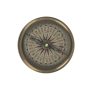 Puede incluir: Una br&uacute;jula de lat&oacute;n vintage con una esfera detallada que muestra las marcas direccionales. La br&uacute;jula tiene una carcasa de color dorado y una aguja que apunta hacia el norte. La esfera incluye marcas de grados y puntos cardinales.
