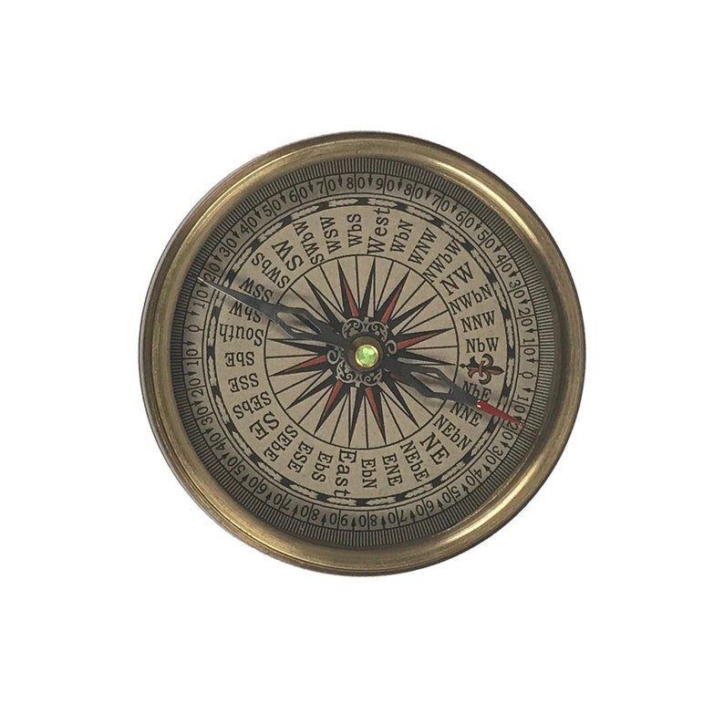 Puede incluir: Una br&uacute;jula de lat&oacute;n vintage con una esfera detallada que muestra las marcas direccionales. La br&uacute;jula tiene una carcasa de color dorado y una aguja que apunta hacia el norte. La esfera incluye marcas de grados y puntos cardinales.
