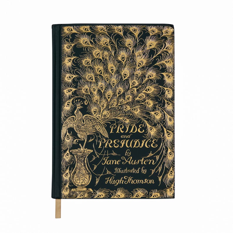 May include: A hardcover book titled "Pride and Prejudice" by Jane Austen, illustrated by Hugh Thomson. The cover is dark teal with gold peacock feather and peacock illustrations. A gold bookmark is attached.
