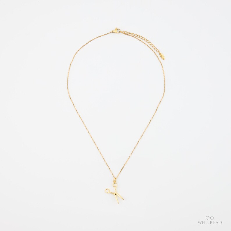 Peut inclure: Un collier en cha&icirc;ne dor&eacute;e avec un petit pendentif en forme de ciseaux dor&eacute;s.
